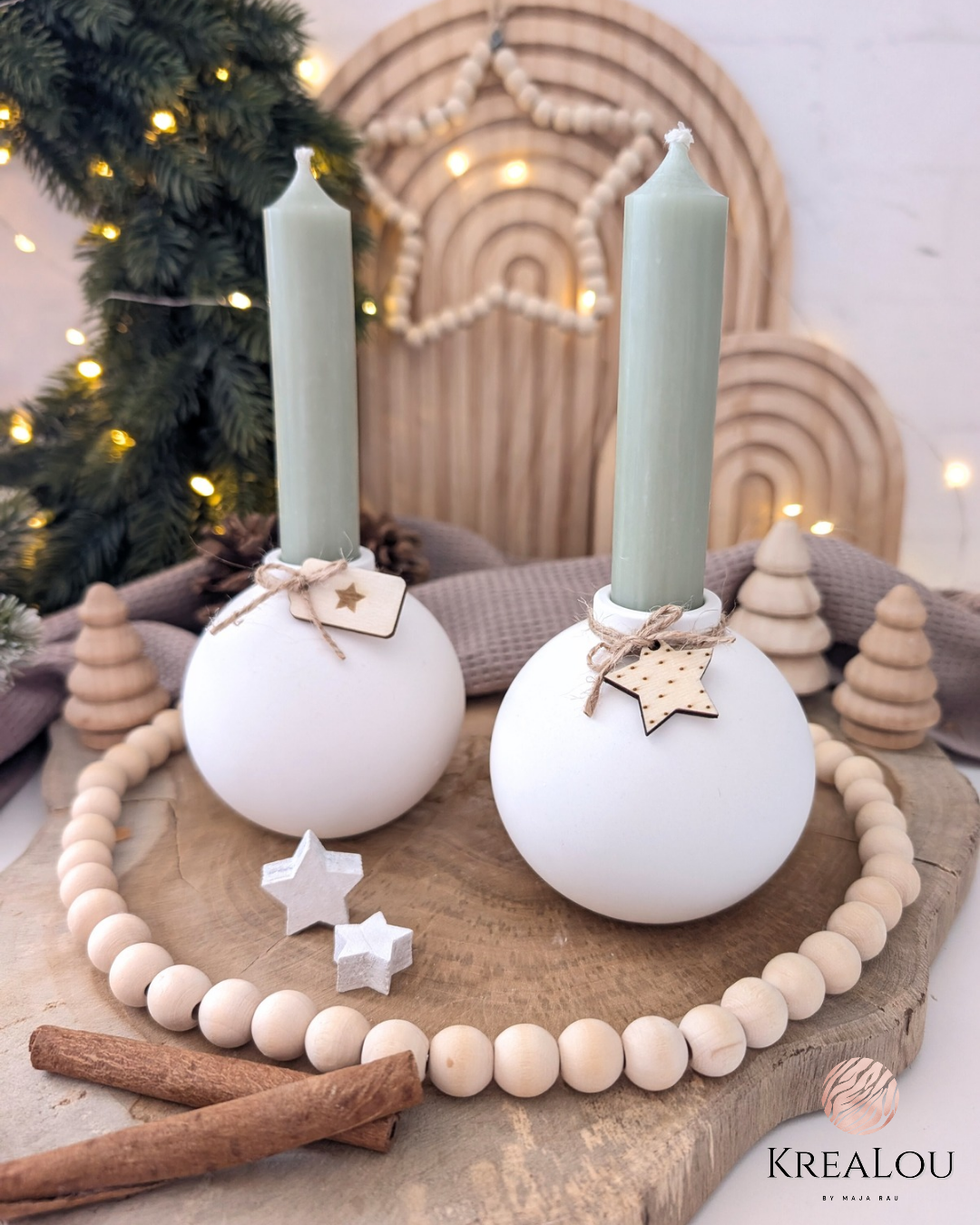 Zwei Kugel-Kerzenhalter mit grünen Stabkerzen, Holzstern-Deko und winterlicher Hintergrundszene; KreaLou Produktfoto.